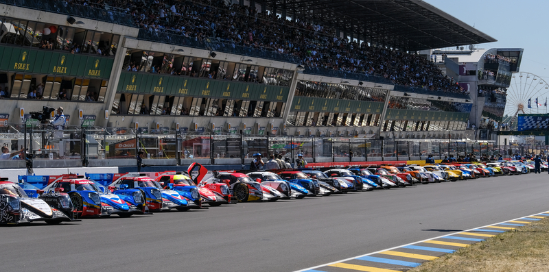 Race cars parked in front of the grandstand at the 24 Hours of Le Mans.