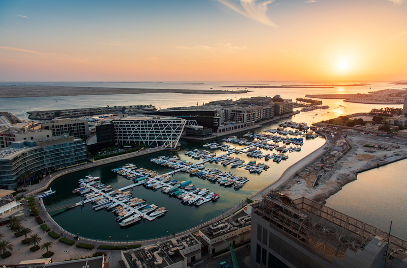 Luxury yachts and superyachts docked in the harbor during sunset at Abu Dhabi International Boat Show.