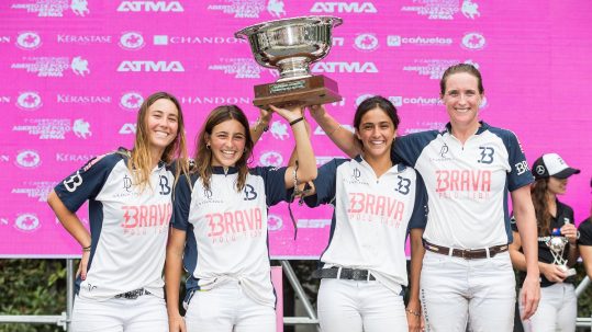 Four female polo players hoisting the trophy of the Argentine Open Women's Polo Championship.