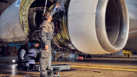 Two technicians working on a big jet engine on Aviation Maintenance Technician Day