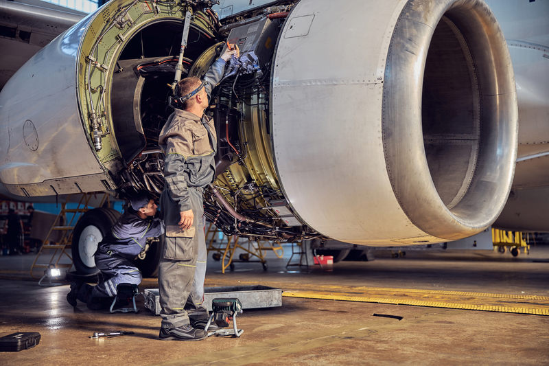 Two technicians working on a big jet engine on Aviation Maintenance Technician Day