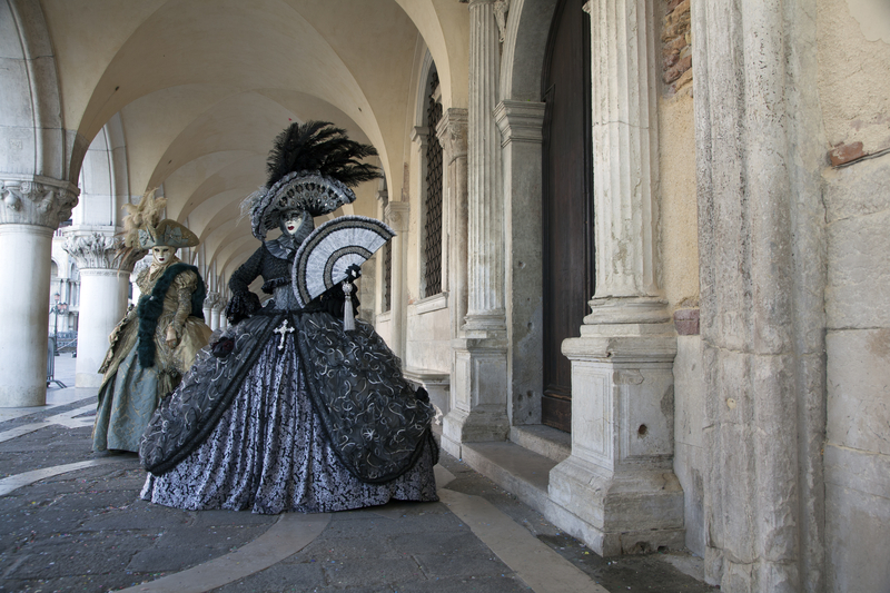 People in masks and elegant Victorian costumes at the Carnival of Venice.