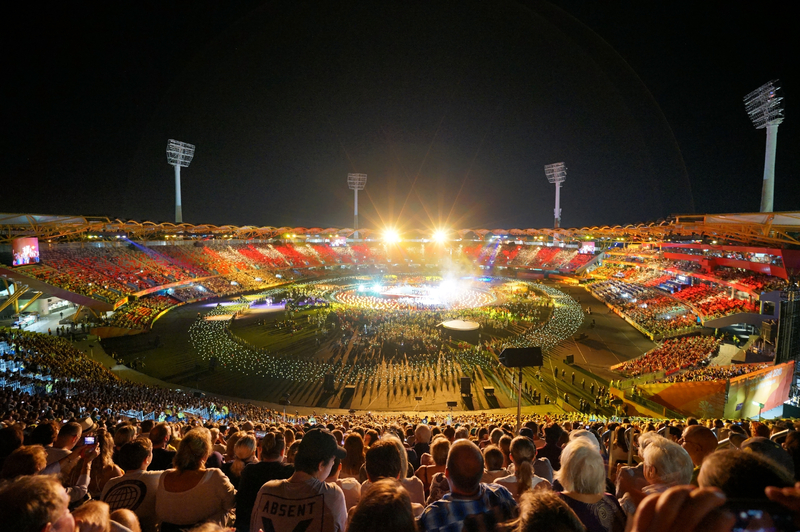 Large stadium lit up at night and filled with people for the Commonwealth Games.