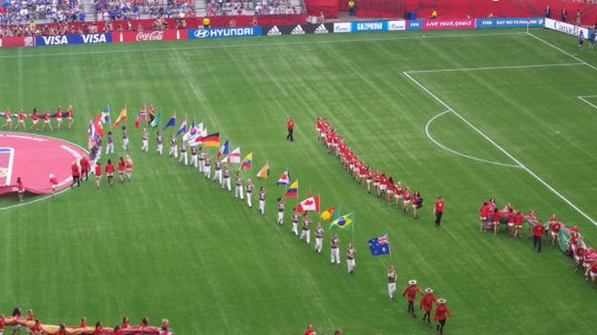 Little girls parading country flags on the field prior to a FIFA Women's World Cup match.