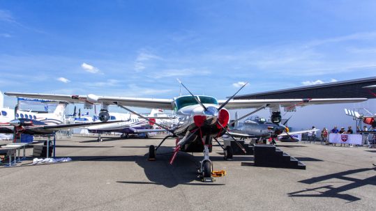Multiple small airplanes parked on the tarmac at the France Air Expo.