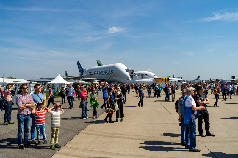 Attendees walking on the tarmac in front of aircraft at the ILA Berlin Air Show.