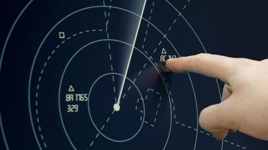Finger pointing at a blip on the radar on International Day of the Air Traffic Controller.