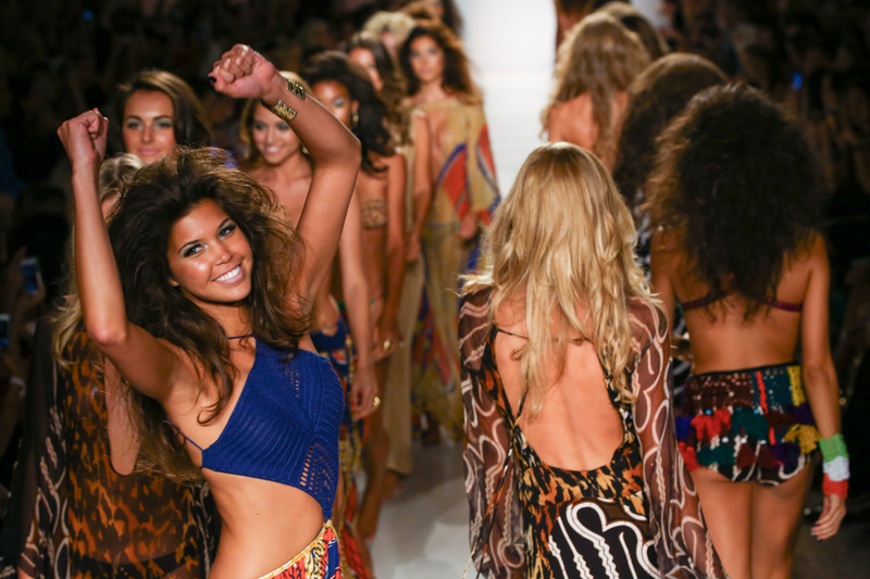 Twelve female models in swimsuits walking the catwalk at Miami Swim Week.