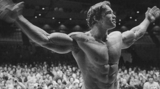 Arnold Schwarzenegger posing in celebration at Mr Universe Championships