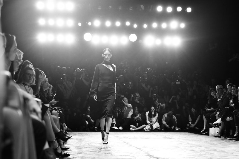Female model walking the catwalk under bright lights at Paris Fashion Week.