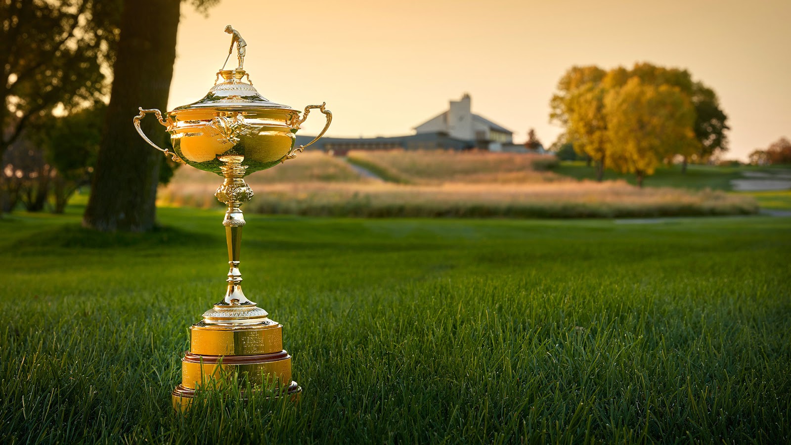 Ryder Cup trophy on a lush green lawn at sunrise.