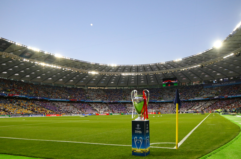 Trophy on the corner of the pitch in front of a full stadium at the UEFA Champions League Final.