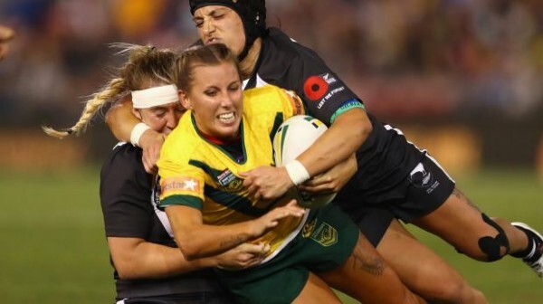 Female rugby player getting tackled by two other players at the Women's Rugby League World Cup
