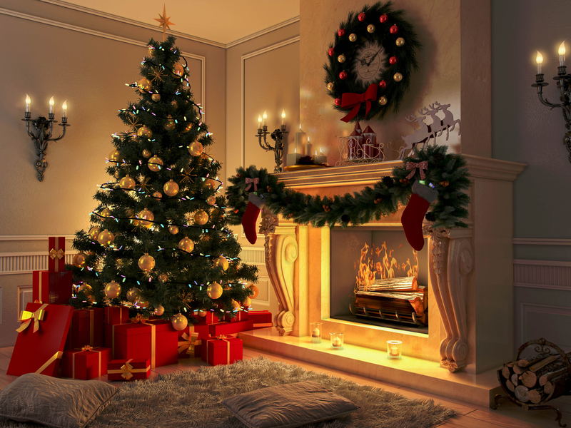 Christmas tree surrounded by presents next to fireplace with a wreath above it.