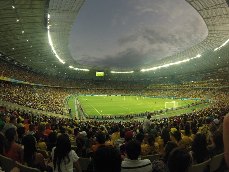 Soccer match being played, surrounded by a full stadium with an open dome at the FIFA World Cup.