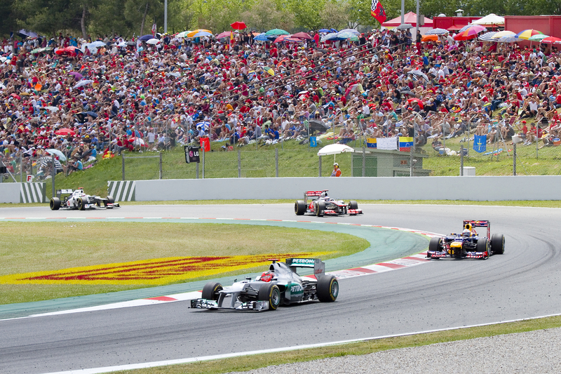 F1 cars racing around a curve at a Formula One Grand Prix.