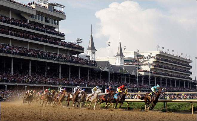 Thoroughbreds racing around the curve in front of the grandstand on the dirt track at the Kentucky Derby.