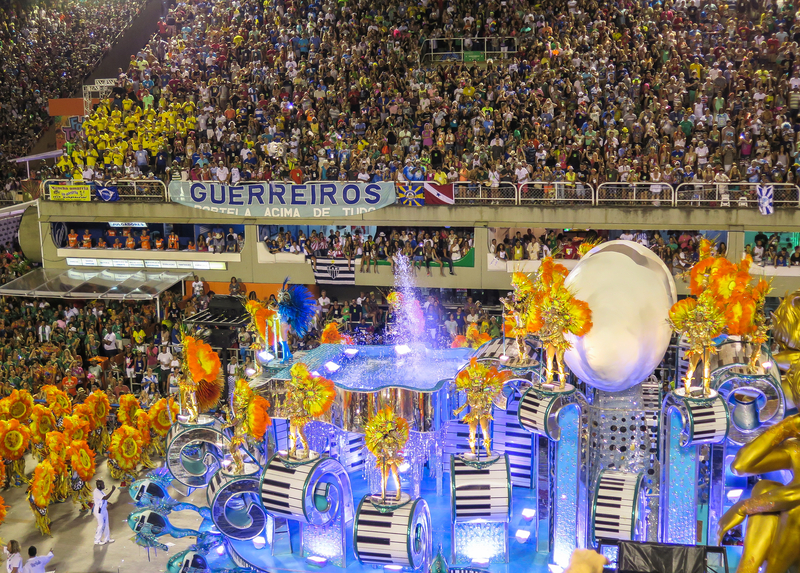 Samba dancers parading on a large float in front of a full stadium at Rio Carnival.