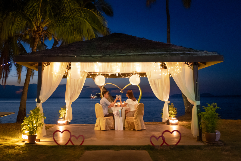 Couple having a romantic dinner under a canopy on the beach on Valentine's Day.