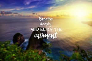 Blurry sunset over the ocean with motivational and inspirational enjoy life quote saying 'Breathe deeply and enjoy the moment'