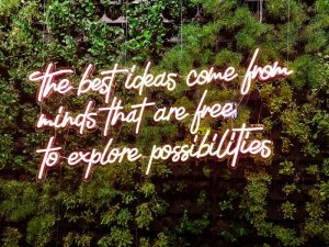 'The best ideas come from minds that are free to explore possibilities' inspirational best explore quote in neon lights on a jungle background to represent exploration.