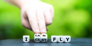 Hand turning dice and changing the expression from 'I can`t fly' to 'I can fly'