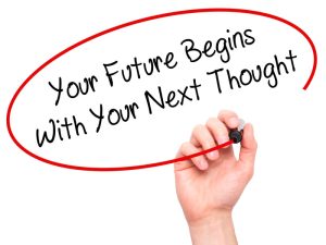 Hand writing an inspirational quote on visual screen with black marker and it says 'Your Future Begins With Your Next Thought'