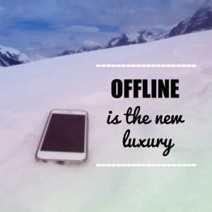 'Offline is the new luxury' quote on blurred snow mountain background