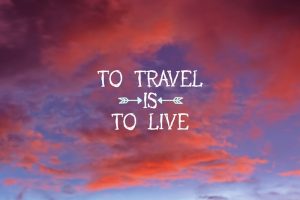 Inspirational and motivational travel quote about traveling to live on an orange and blue sunset.