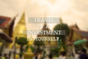 Blurry vacation destination background with the travel quote about 'Traveling is an investment in yourself.'