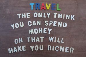 Creative composition with wooden letters celebrating a motivational quote about the only thing you can spend money on that will make you richer.