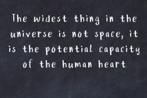 Motivational quote about the capacity of the human heart for love written on black chalkboard.